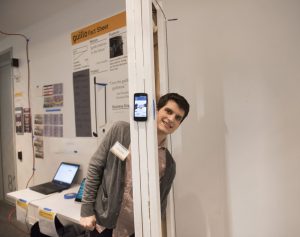 Student interacting with a student project which includes a physical installation and mobile phone at IDM showcase 2018