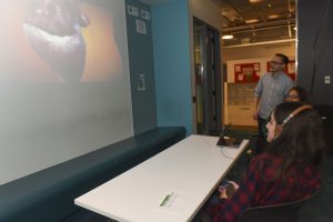 people watching a student's work projected on a wall at IDM showcase 2017