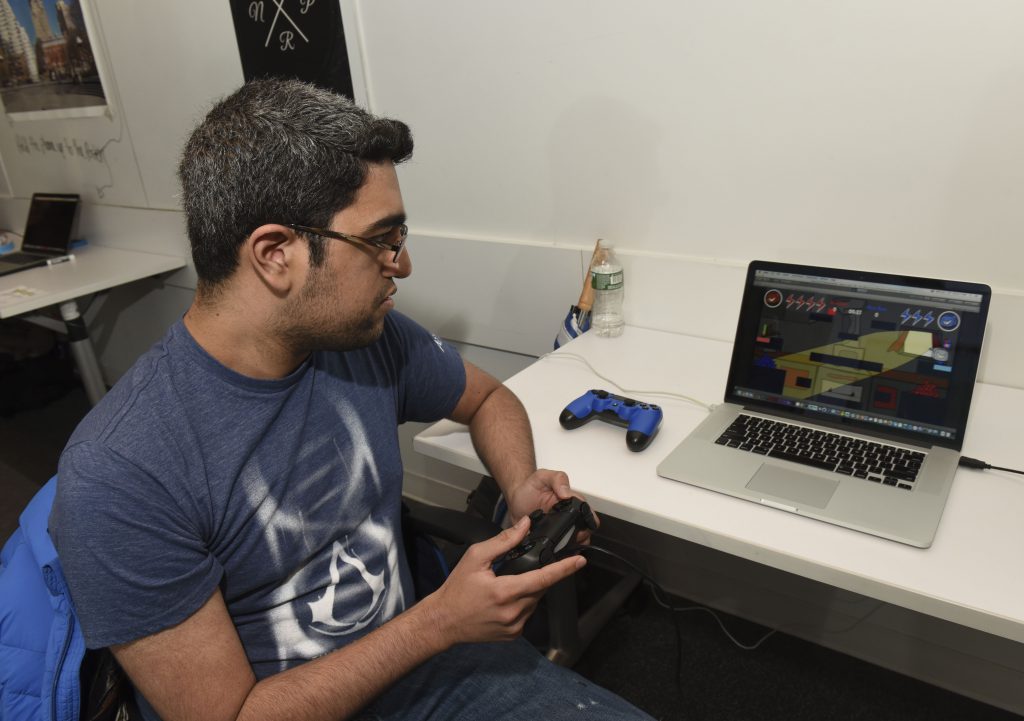 student interacting with a project which is a laptop game with controllers at IDM showcase 2017