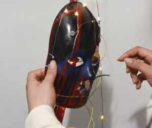 Student interacting with a physical prototype which is a mask with LED lights at IDM showcase 2017