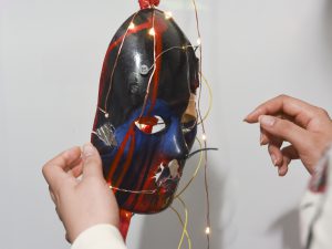 Student interacting with a physical prototype which is a mask with LED lights at IDM showcase 2017