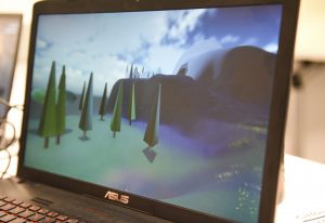 Student project on a laptop at IDM showcase 2017 showing a 3D landscape with trees, mountains and clouds in the sky