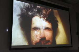 Student project projected on a screen at IDM showcase 2017 showing a person's face submerged in water