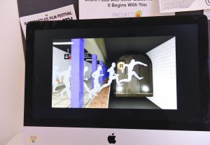 Student project on a monitor at IDM showcase 2017 showing white body shadows jumping in front of a subway train