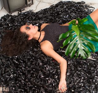 Diana Castro NYU IDM Alumni posing on what looks like a bunch of cassette tape rolls