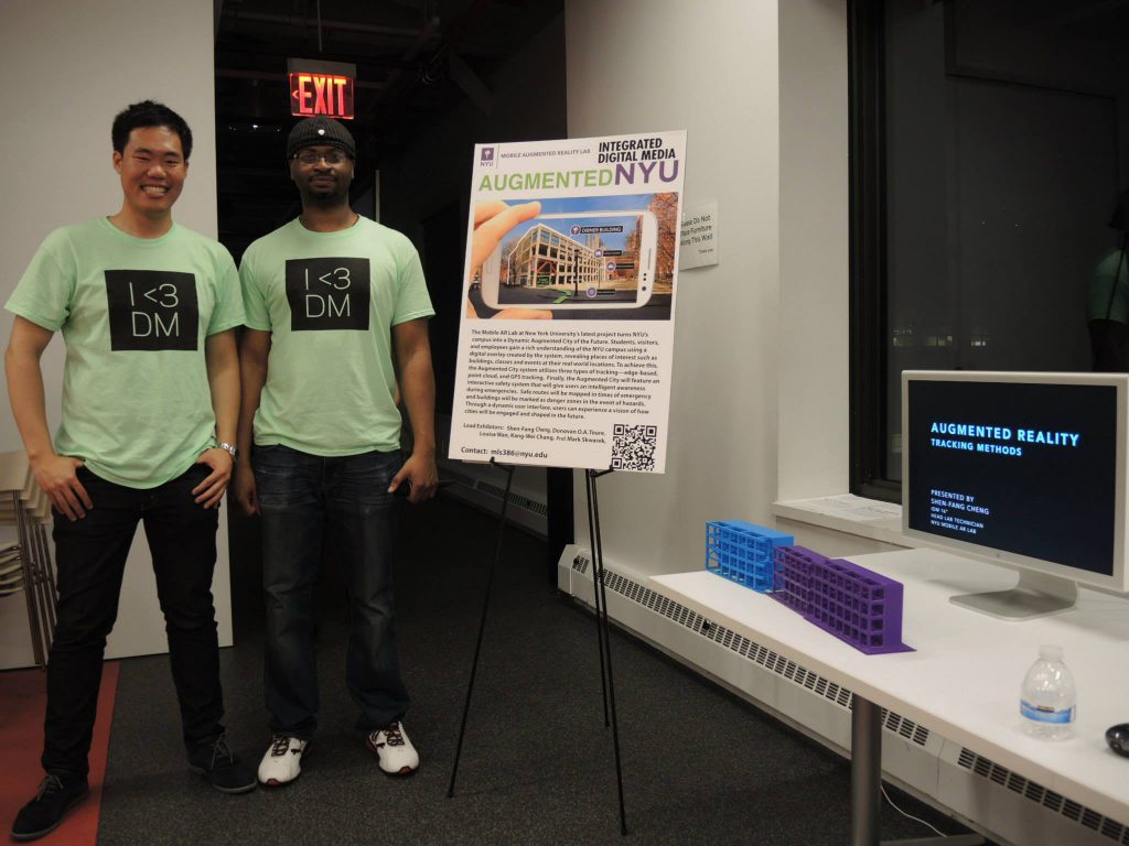 Students standing next to their project's printed documentation at IDM 2015 showcase