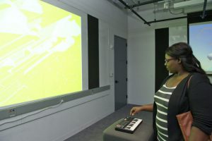 student interacting with a screen projected project using a musical keyboard at IDM 2016 showcase