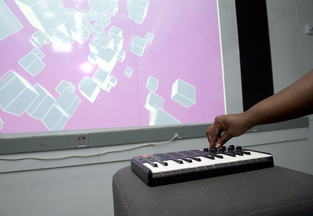student interacting with a screen projected project through a musical keyboard at IDM 2016 showcase